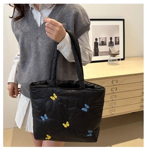 Close-up of butterfly embroidery on a black quilted tote bag for a textured autumn style