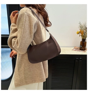 Close-up of retro brown faux leather baguette bag worn over the shoulder with knit top