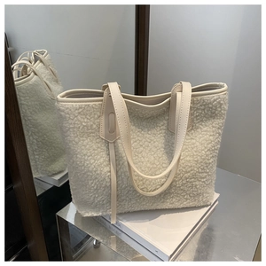 Gros plan sur la texture peau de mouton crème et les bordures en cuir du sac cabas