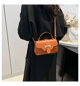 Chic orange-brown stone pattern handbag with gold H-buckle shown on a shoulder strap