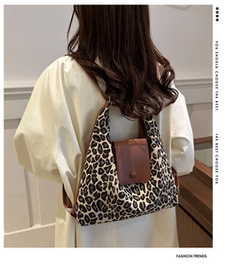 Detail view of the leopard print canvas tote bag with a brown leather flap on a model