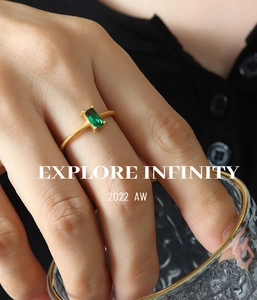 Detail view of gold ring featuring a rectangle emerald green zircon on a model's hand
