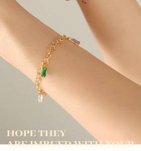 Detail of heart-shaped link bracelet with colorful rectangular gemstones on a model wrist