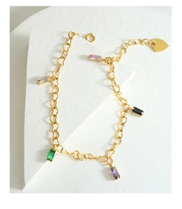 Detail of gold-plated chain bracelet with multi-colored rectangular gemstones and heart charm