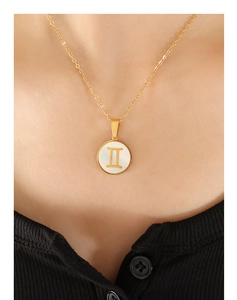 Gros plan du collier Gémeaux plaqué or 18 carats avec pendentif en nacre sur un mannequin