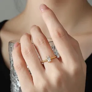 Gold ring with emerald-cut cubic zirconia worn by model holding a glass cup