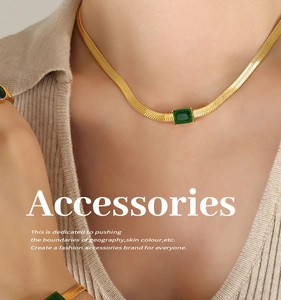Close-up of gold snake chain set with emerald-cut green gemstones on model