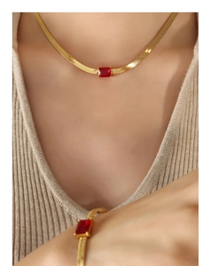 Close-up of golden blade chain necklace with square red zircon gemstone on a model