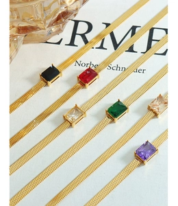 Detail of gold snake chains with colorful rectangular zircons on a fashion magazine