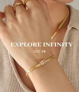 Detail of gold blade chain bracelet with rectangular zircon on model wearing a gold ring
