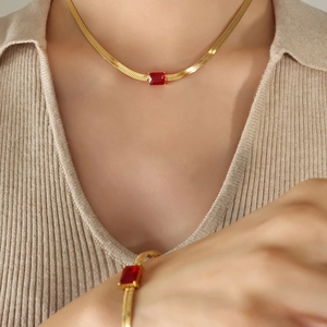 Golden snake chain necklace set with rectangular red zircon pendant worn on a model
