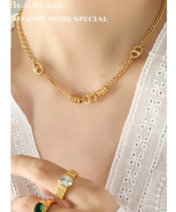 Primer plano detallado del collar dorado de eslabones planos y anillos con piedras
