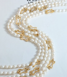 Dettaglio collana di perle d'acqua dolce a strati con stelle dorate su sfondo di rivista
