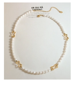 Dettaglio della collana di perle d'acqua dolce con farfalle dorate e chiusura a moschettone