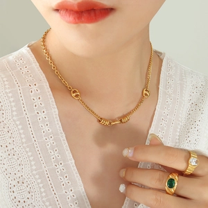 Collar de eslabones de morro de cerdo dorado y anillos con piedras en una modelo