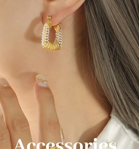 Macro view of gold-plated U-shaped earrings with twisted texture and micro pearl inlay