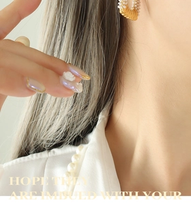 Macro shot of U-shaped gold plated pearl earrings on model showing fine vintage details