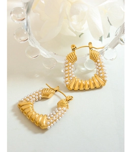 Detail of gold U-shaped hoop earrings with pearls and pleated metal texture