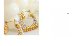 Close-up of gold-plated twisted rope hoop earrings with small white pearl inlays