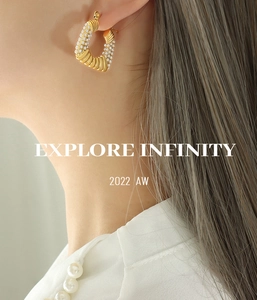 Detailed side view of C-shaped gold-plated hoop earrings with pearls on a model