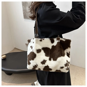 Détail d'un sac à bandoulière en peluche avec motif vache et sangle en cuir
