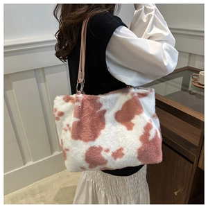 Detail der flauschigen Plüschtasche mit rosa Kuhmuster und silbernen Beschlägen