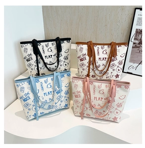 Detail of four large tote bags featuring cute cartoon prints and vibrant color handles