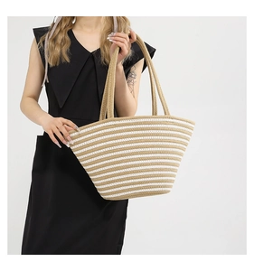 Détail d'un grand sac cabas en paille à rayures marron et blanc porté par un modèle