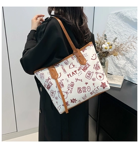 Close-up of a large tote bag with bear graffiti prints and brown leather straps