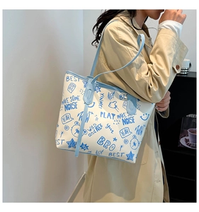 Detail of blue graffiti print tote bag showing artistic patterns and shoulder strap design
