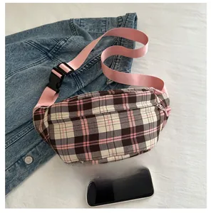 Detail of pink plaid chest bag with adjustable woven strap and secure zipper closure