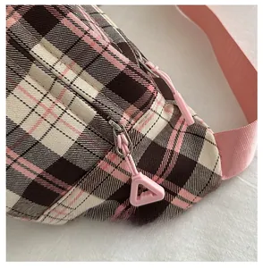 Close-up of pink and brown plaid waist bag featuring a smooth zipper and nylon strap