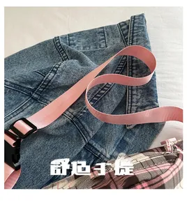 Detail of pink woven strap with plastic buckle on a plaid pattern crossbody bag