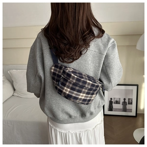 Detailed view of a casual plaid crossbody bag worn by a model in a modern home setting