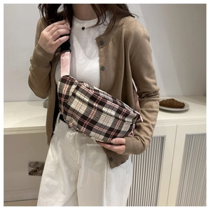 Close-up of pink and brown plaid crossbody bag with nylon strap on a model