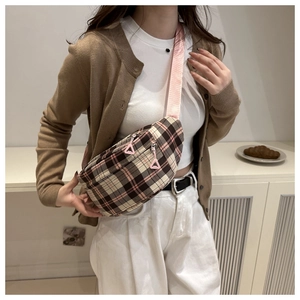 Detail of checkered crossbody bag with pink adjustable strap and dual zipper pockets