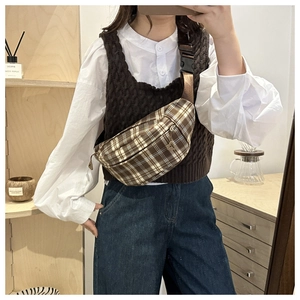 Detail of checkered brown crossbody bag with adjustable strap worn across the chest