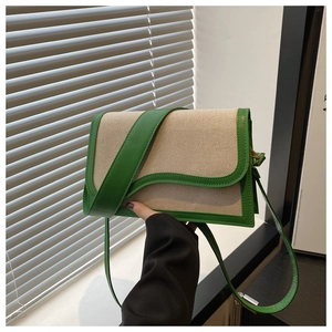 Detail of canvas crossbody bag featuring green leather trim and wave-shaped flap design