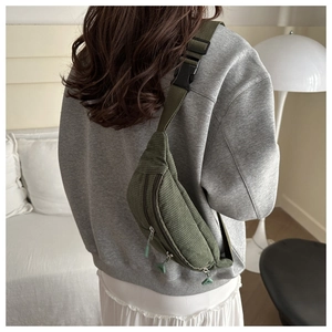 Detail of olive green corduroy waist bag with adjustable strap and metal zippers