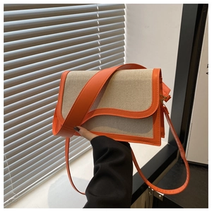 Detailed view of cream fabric bag with orange leather trim and modern wavy flap design