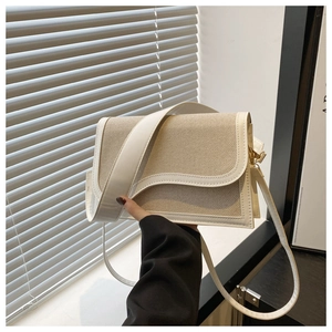 Detail of a beige woven shoulder bag with wavy white leather trim and adjustable strap