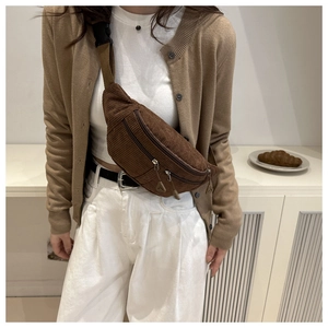 Close-up of brown corduroy crossbody saddle bag with multiple zippers and adjustable strap