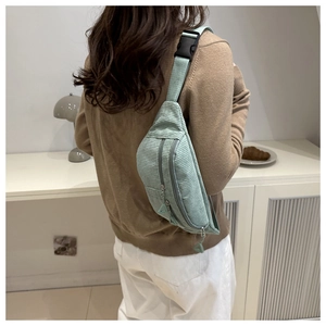 Detail of mint green corduroy crossbody bag with double zippers and adjustable strap