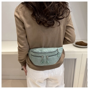 Detail of light green corduroy fanny pack showing soft ribbed texture and dual zippers