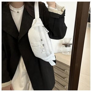 Detailed shot of white corduroy crossbody bag with adjustable strap and triangle zippers