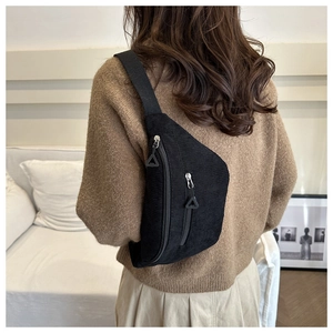 Retro black corduroy crossbody bag with double zippers worn over a cozy sweater