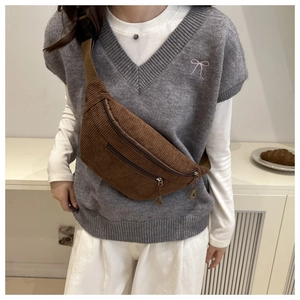 Detailed view of brown corduroy crossbody bag worn as a waist pack on casual attire