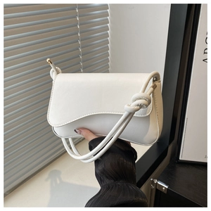 Detail of white leather shoulder bag featuring unique knotted strap and curved flap design