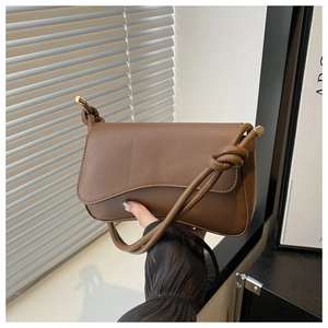 Detail of coffee brown shoulder bag with knotted strap and gold metal hardware