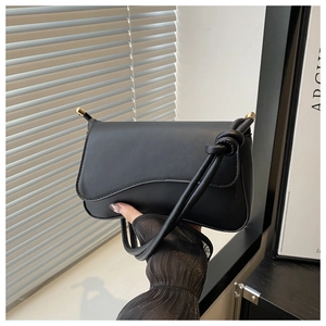 Detail of matte black leather bag with wave flap and gold hardware accents